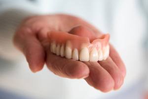 Close-up of hand holding dentures in Palm Bay, FL