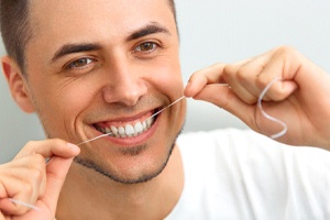 smiling man flossing his teeth