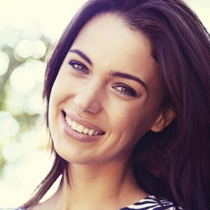 Brunette lady tilting her head smiling after periodontal therapy