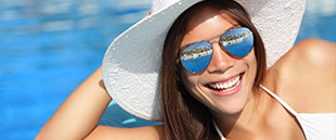 Woman in sun hat sharing flawless smile after cosmetic dentistry