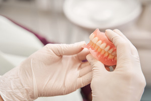 Close-up of gloved hands holding dentures